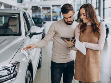 Frau zeigt Mann ein Autoverkauf Angebot auf dem Tablet bei Autoankauf Haan
